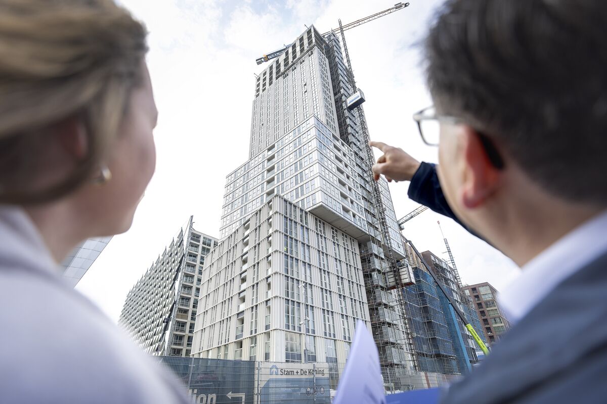 Un homme et une femme regardent un gratte-ciel gris en construction.