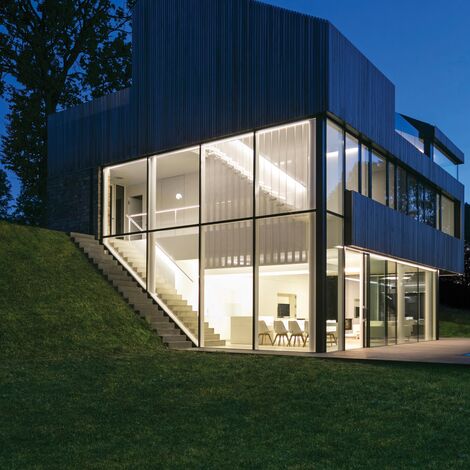 Well-lit private home with lots of glass at night.