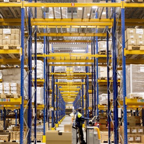 Warehouse worker transporting goods through storage aisles