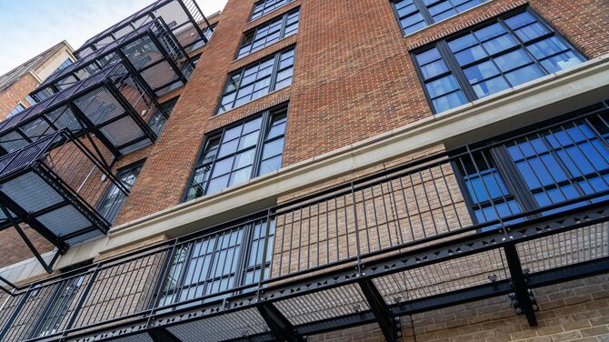 Immeuble d'appartements de hauteur moyenne en brique avec fenêtres aspect acier.