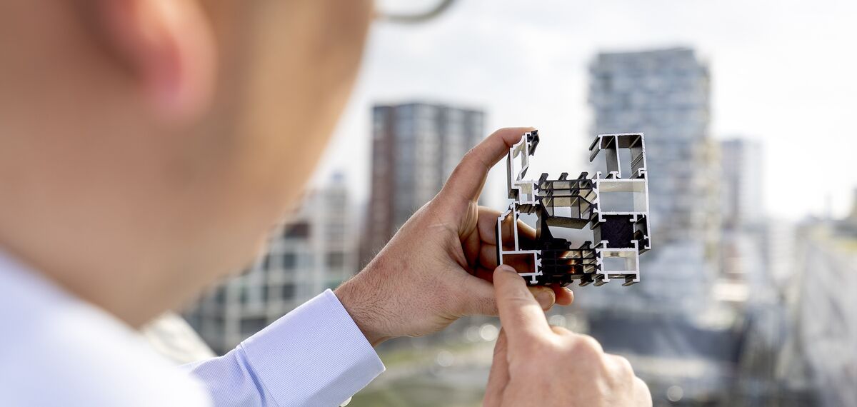 Man holding and pointing at aluminium section sample.