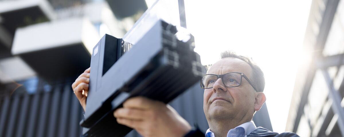 Un homme portant des lunettes regarde attentivement un échantillon de coin en aluminium.