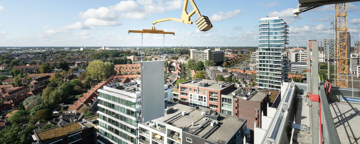 Panneau de construction modulaire soulevé à côté d'un gratte-ciel.