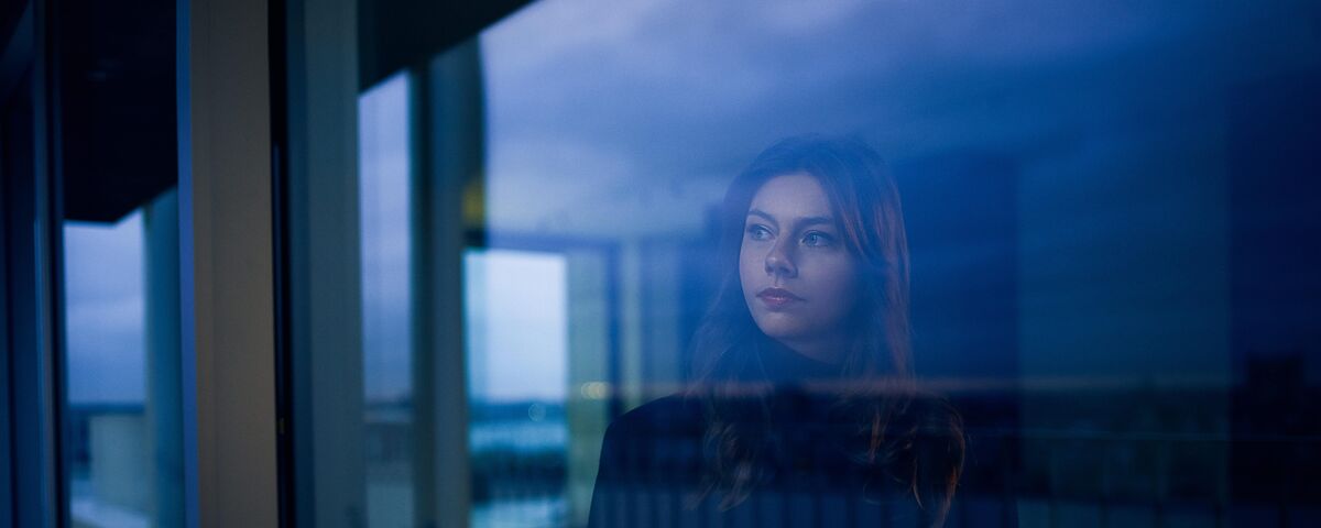 Woman looking out of window at nightfall.