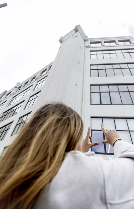 Woman looking and pointing at mid-rise white office building in the Netherlands.