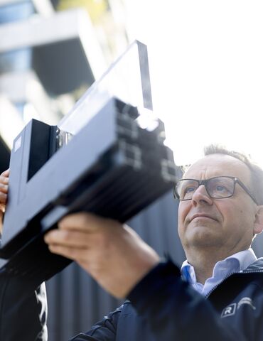 Un homme portant des lunettes regarde attentivement un échantillon de coin en aluminium.