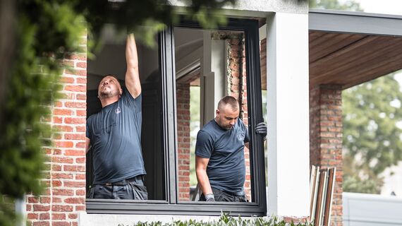 Two installers placing new aluminium profiles in renovated home.