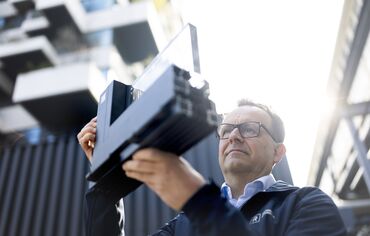 Man with glasses looking closely to aluminium corner sample.
